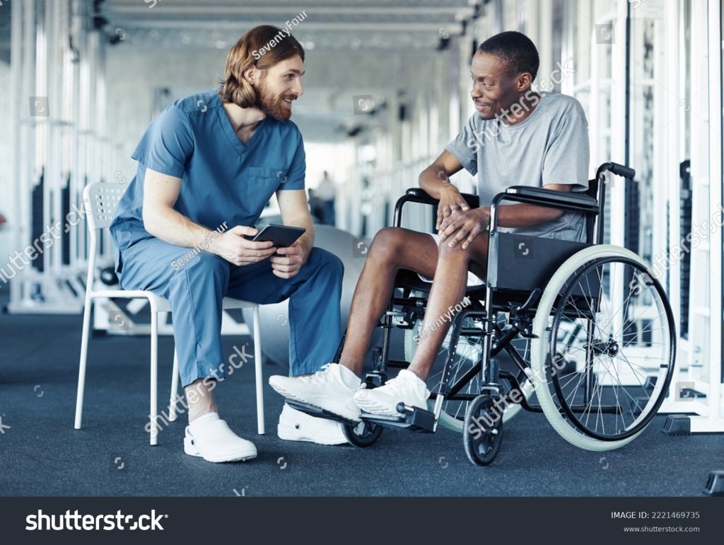 medcare vacances - stock photo doctor in uniform discussing sport training with patient while he sitting in wheelchair and 2221469735